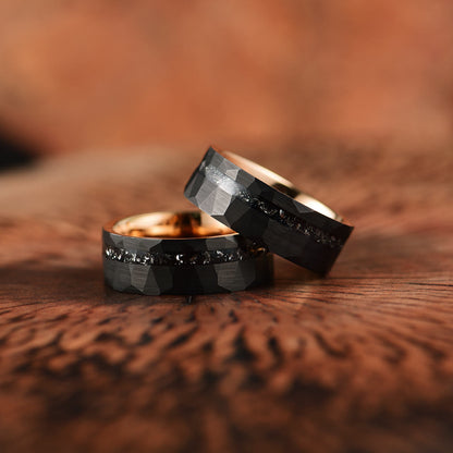 Zwei schwarze Eheringe mit Diamanten, facettiert, auf Holzoberfläche.