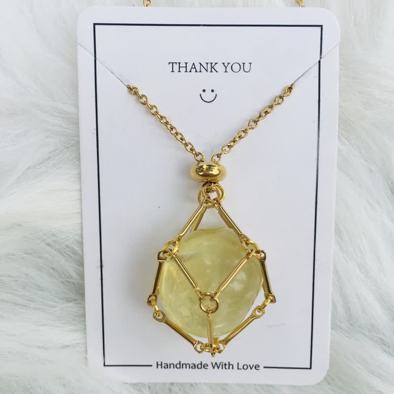 Goldene Halskette mit gelbem Edelsteinanhänger, handgefertigt, auf weißem Hintergrund.