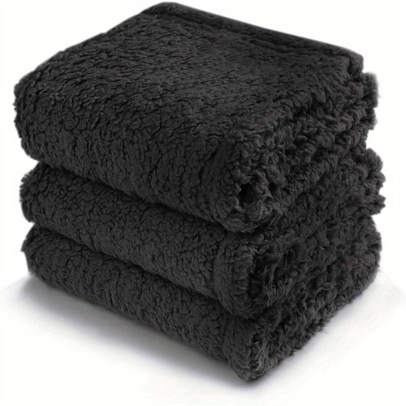 Dunkle, flauschige Fleece-Decke, gestapelt, weich, warm, ideal für Sofa oder Bett.
