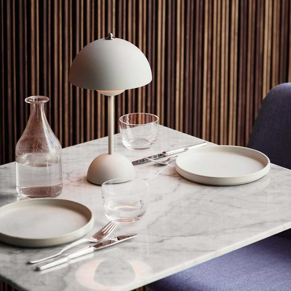 Moderne Tischlampe auf Marmortisch mit Geschirr und Gläsern, skandinavisches Design, minimalistisch.