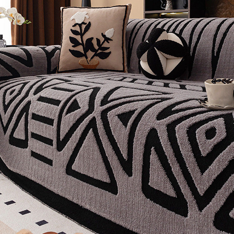 Soffa med grått överdrag och svart geometriskt mönster av trianglar och romber, med blomkudde 15