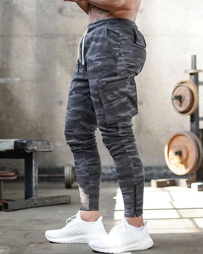 Mann in grauer Camouflage-Jogginghose im Fitnessstudio, weiße Sneaker, sportlich, modern.