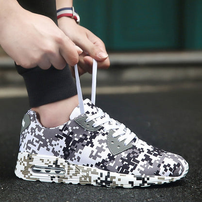 Person bindet Schnürsenkel von schwarz-weißen Camouflage-Sneakern auf Asphalt.