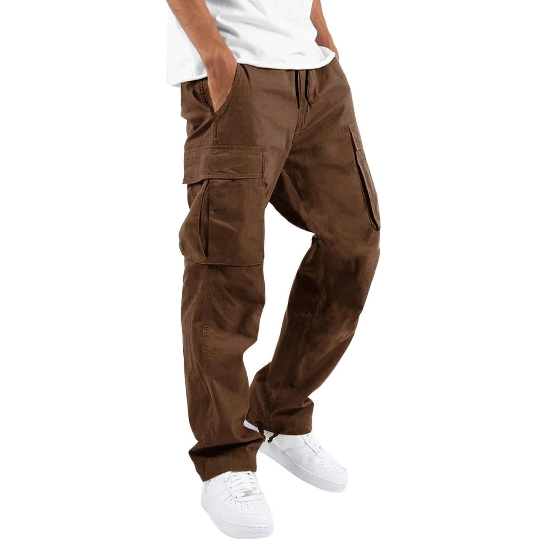 Man bär mörkbruna cargobyxor med sidfickor och justerbar midja, vit t-shirt och vita sneakers, snett framifrån. 5