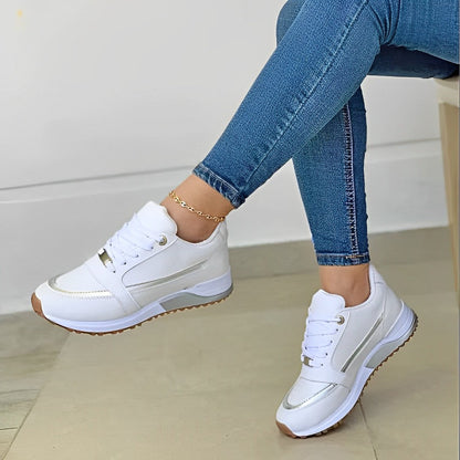 Weiße Damen-Sneaker mit goldenen Akzenten, kombiniert mit blauen Jeans, modisch und bequem.