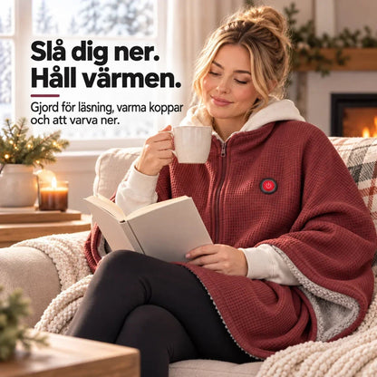 Kvinna i röd huvförsedd poncho läser en bok i soffan med kopp och brasa 10