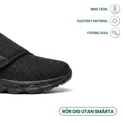 Närbild på bred tå på svart mesh-sko, med ikoner för elastiskt material och flexibel sula. 14