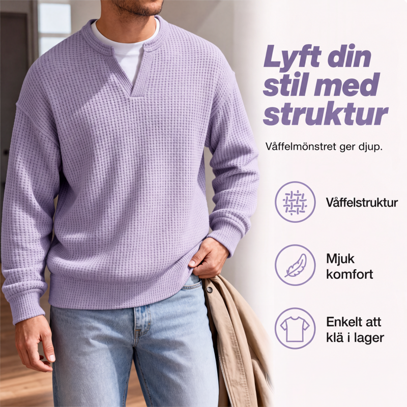 Närbild på lila våffelstickad topp med V-ringning över vitt linne, buren av man med beige jacka över armen. 3