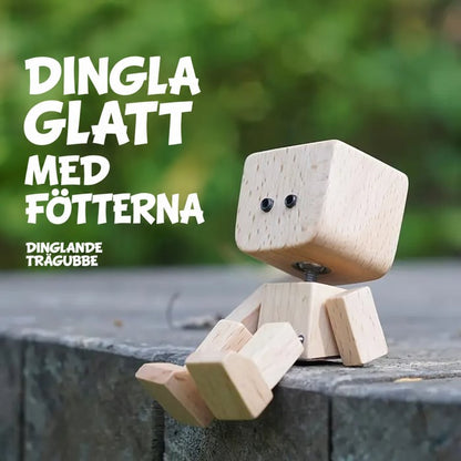 Trämannen sitter på en stenkant med benen hängande, grön suddig bakgrund och text om att vicka med fötterna. 15