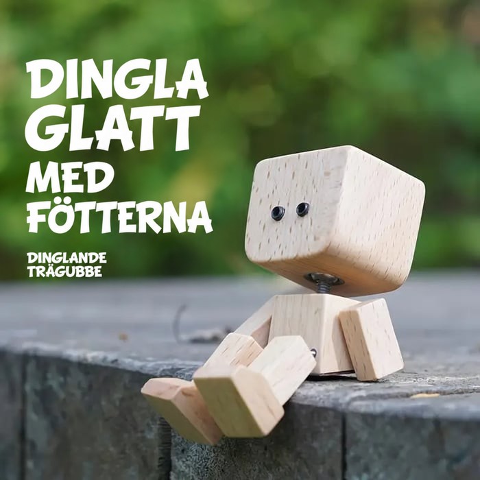 Trämannen sitter på en stenkant med benen hängande, grön suddig bakgrund och text om att vicka med fötterna. 13