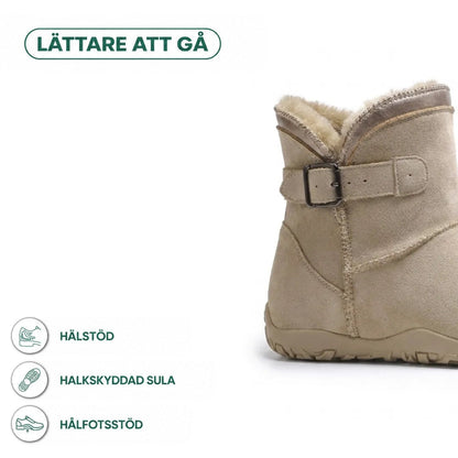 Beige känga med spänne i närbild, med ikoner för hälstöd, halkfri sula och hålfotsstöd 4