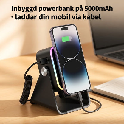 Mobil laddas via kabel från ställets inbyggda powerbank, med spiralkabel och laptop på skrivbordet 5