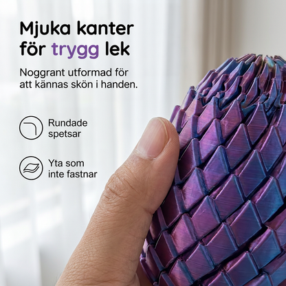 Närbild på en tumme som håller ett lila drakägg, där de rundade fjällspetsarna och den släta ytan syns. 3