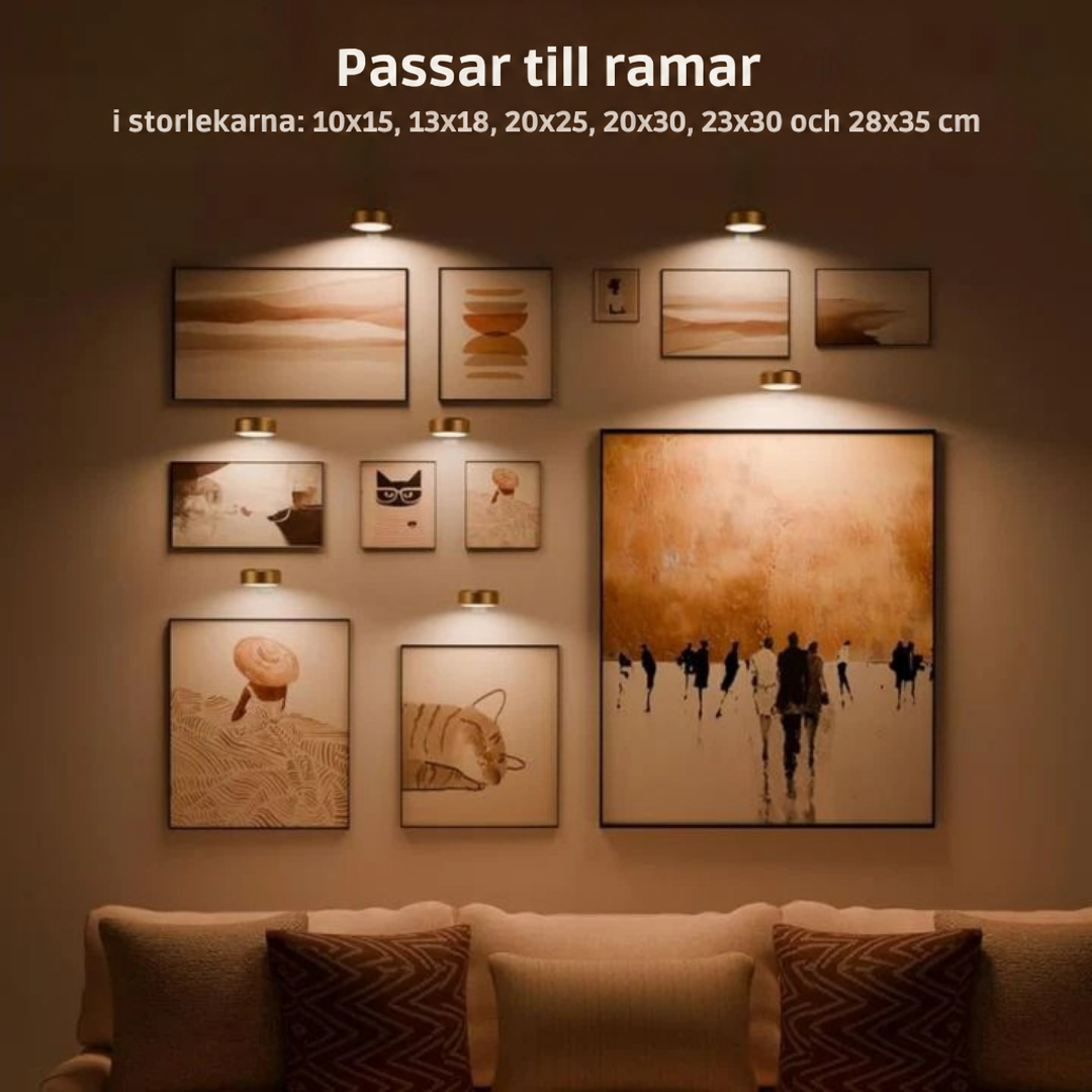 Flera mässingsfärgade lampor lyser upp ett galleri med inramade tavlor i olika storlekar ovanför en soffa 2