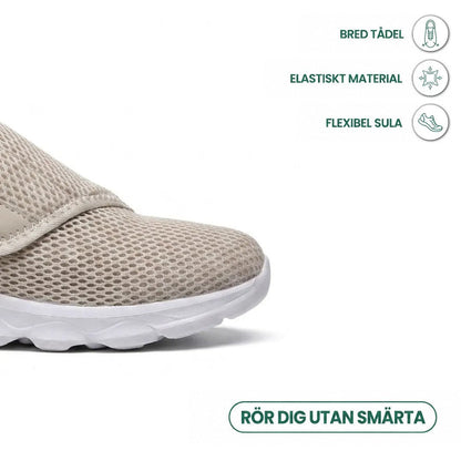 Närbild på tåpartiet av beige mesh-sko med vit sula, med ikoner för bred tåbox, elastiskt material och flexibel sula. 32