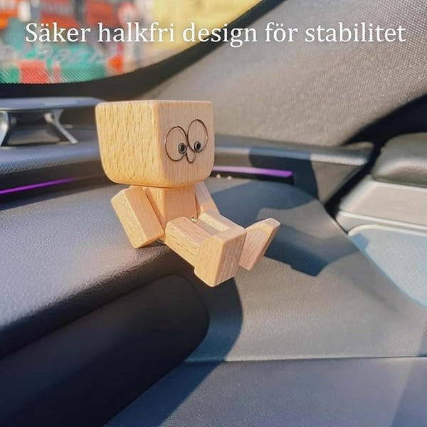 Trämannen med stora ögon sitter på en mörk instrumentbräda med benen framåt, med text om halkfri design. 12