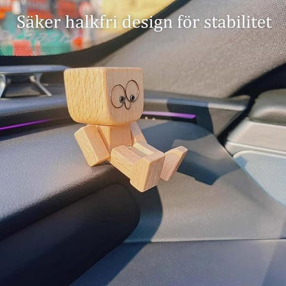 Trämannen med stora ögon sitter på en mörk instrumentbräda med benen framåt, med text om halkfri design. 12