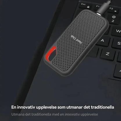 Extern SSD med ansluten kabel ligger på ett laptoptangentbord, sedd uppifrån 2