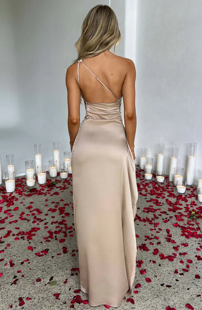 Frau in champagnerfarbenem Satin-Maxikleid, umgeben von Kerzen und Rosenblättern.