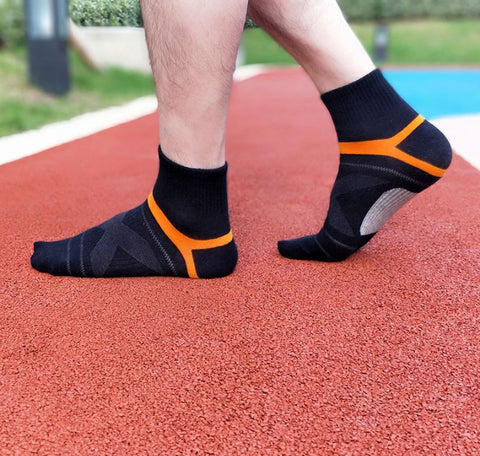 Schwarze Kompressionssocken mit orangefarbenen Akzenten auf rotem Laufbahnuntergrund.