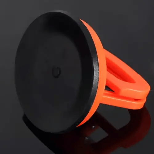 Orange sugkopp sedd från undersidan med den släta svarta gummiskivan som fäster mot bilplåten, mot mörk glänsande bakgrund. 3