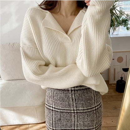 Frau in cremefarbenem Strickpullover und karierter Rock, gemütliche Herbstmode.