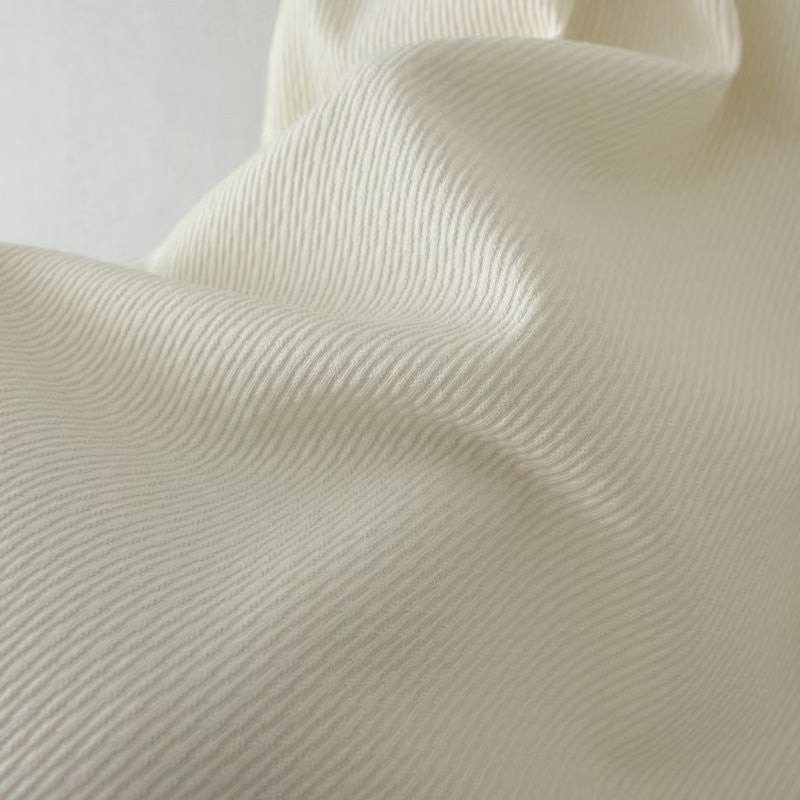 Cremefarbener Baumwollstoff mit feiner Rippstruktur, ideal für Bekleidung und Heimtextilien.