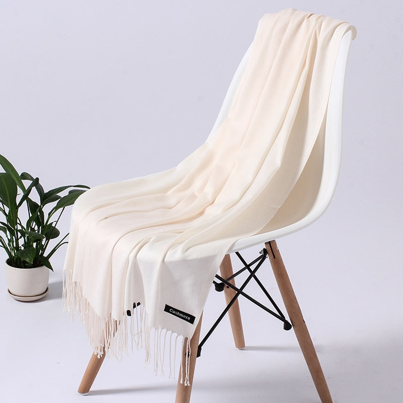 Cremefarbener Kaschmirschal auf weißem Stuhl, weiches Material, elegantes Design, Wohnzimmer-Deko.