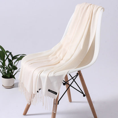 Cremefarbener Kaschmirschal auf weißem Stuhl, weiches Material, elegantes Design, Wohnzimmer-Deko.