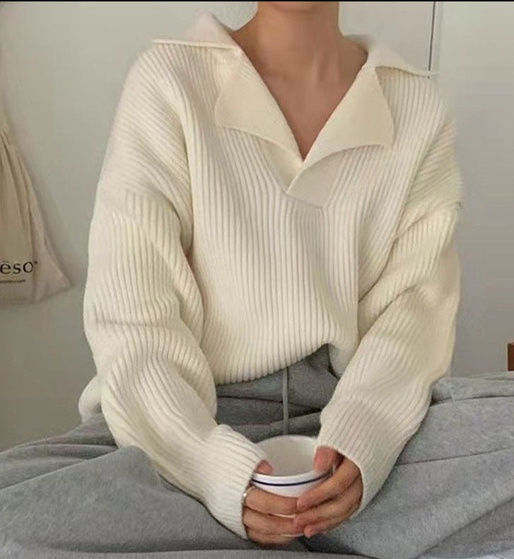 Frau in cremefarbenem Strickpullover hält Tasse, gemütliche Herbstmode, lässiger Stil.
