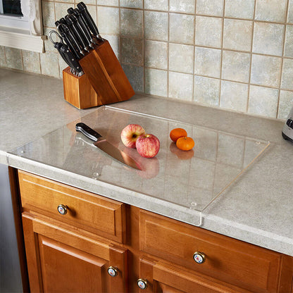 Klarglas-Schneidebrett auf Küchenarbeitsplatte mit Messer, Äpfeln und Tomaten.