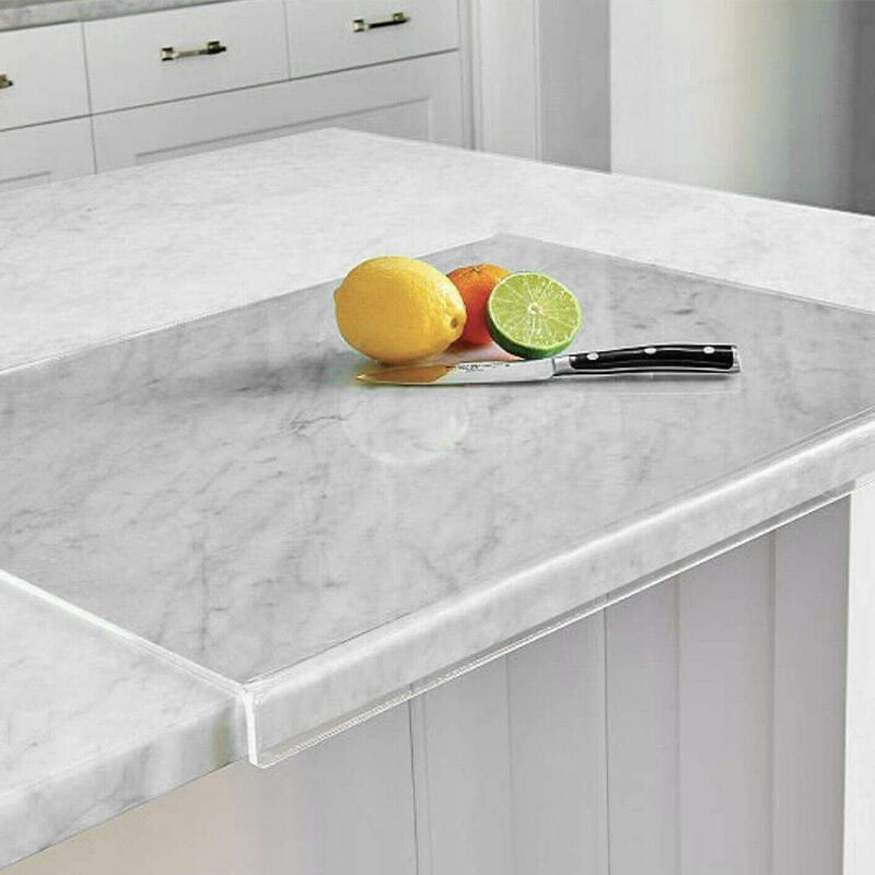 Glas-Schneidebrett auf Marmorarbeitsplatte mit Zitrone, Limette, Messer in moderner Küche.