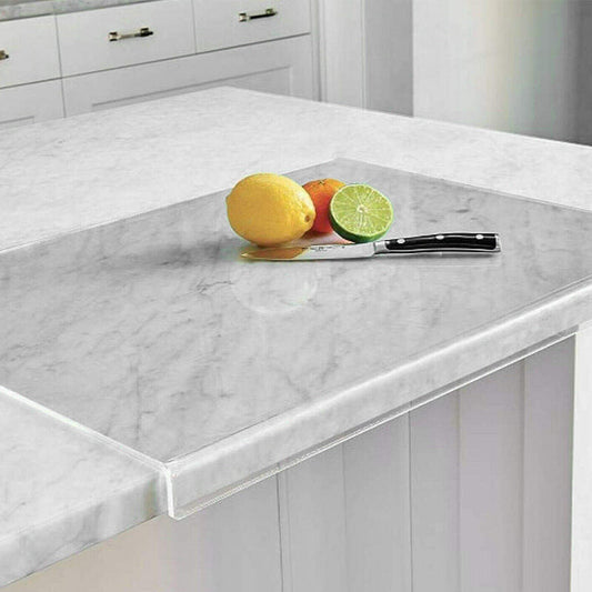Glas-Schneidebrett auf Marmorarbeitsplatte mit Zitrone, Limette, Messer in moderner Küche.