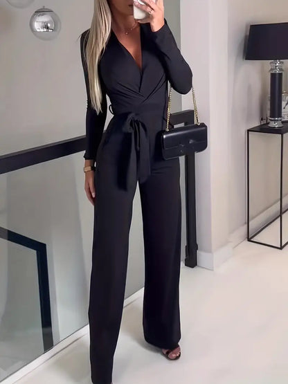 Frau in schwarzem Jumpsuit mit Gürtel, schwarze Handtasche, elegantes Outfit, moderne Mode.