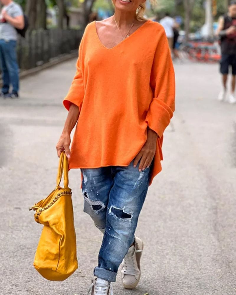 Frau in orangefarbenem Pullover, zerrissene Jeans, gelbe Tasche, Straße, lässige Mode.
