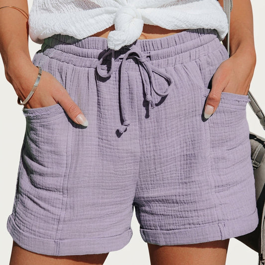 Samma shorts i ljuslila, buret med vit knutad topp, händerna i de påsydda fickorna och uppvikta benkanter. 2