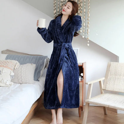 Frau im blauen Fleece-Bademantel mit Kaffeetasse im Schlafzimmer, gemütliche Morgenroutine.