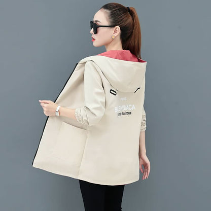 Frau mit beiger Kapuzenjacke, rotem Innenfutter, Sonnenbrille, modisch, seitliche Ansicht.