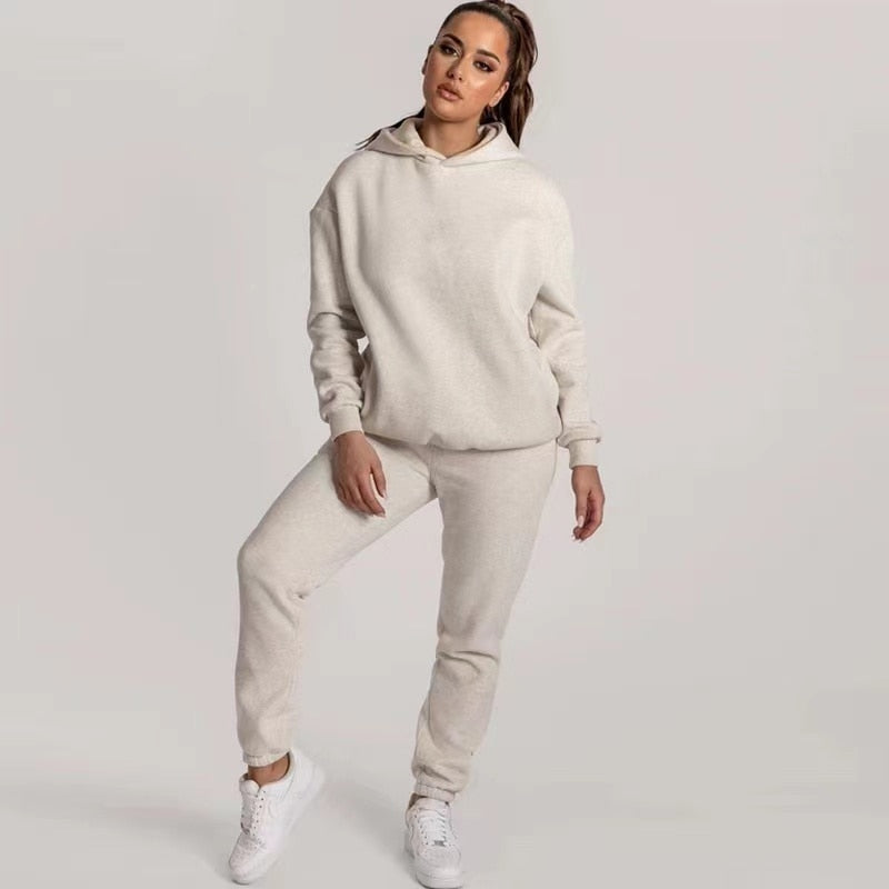 Frau in beigem Hoodie und Jogginghose, Freizeitmode, bequeme Kleidung, weiße Sneaker.