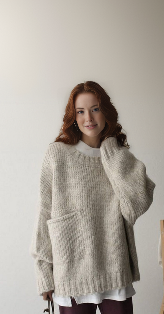 Eine Frau trägt einen beigen Strickpullover mit Tasche, lässiger Herbstmode.