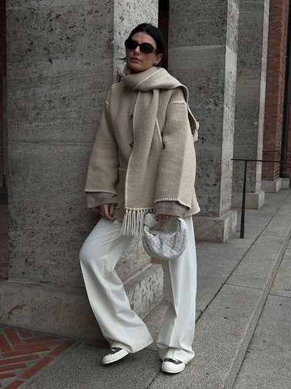 Frau in beiger Wolljacke mit Schal, weiße Hose, Sonnenbrille, modisch, Herbstmode.