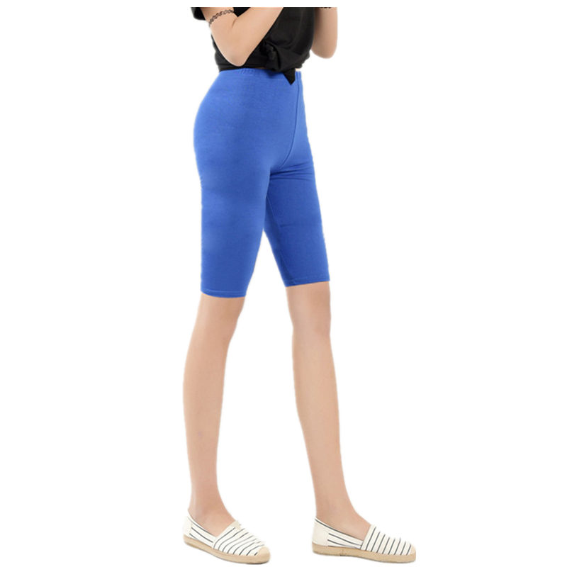Frau in blauer Radlerhose, schwarze Bluse, weiße Schuhe, Mode, Sportbekleidung, Sommeroutfit.
