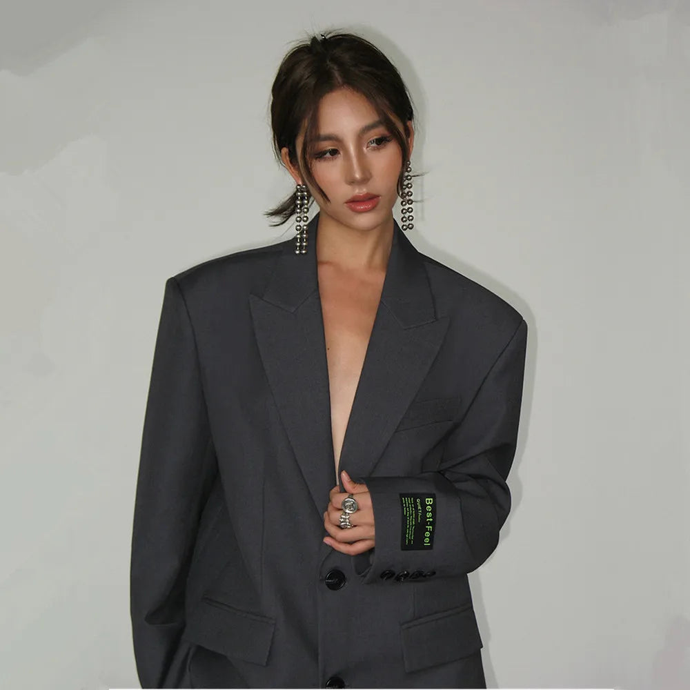 Frau in grauem Oversize-Blazer, modisch, Büro-Look, weite Schultern, elegantes Design.