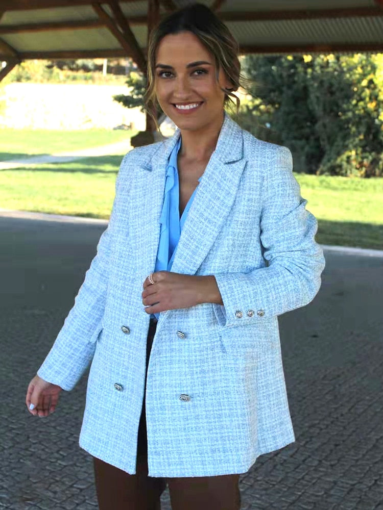 Frau in hellblauem Tweed-Blazer, doppelt geknöpft, modisch, elegant, draußen.