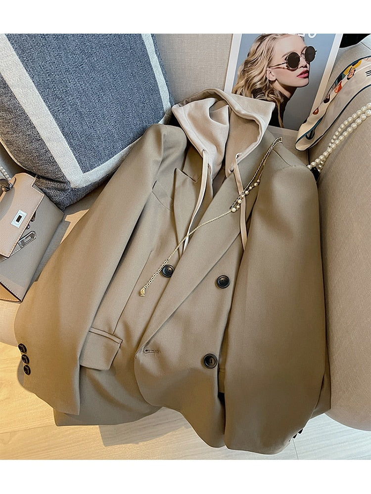 Beiger Blazer mit Kapuze, Damenmode, eleganter Stil, Herbstkollektion, auf Sofa drapiert.