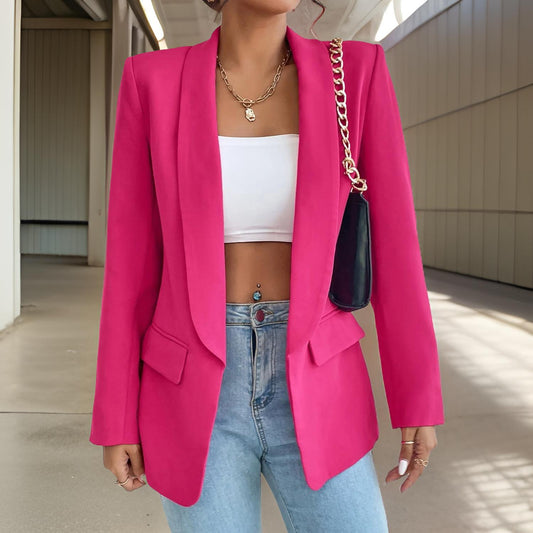 Frau in pinkem Blazer, weißem Top, blauer Jeans, schwarze Tasche mit Kettengurt, modisch, elegant.