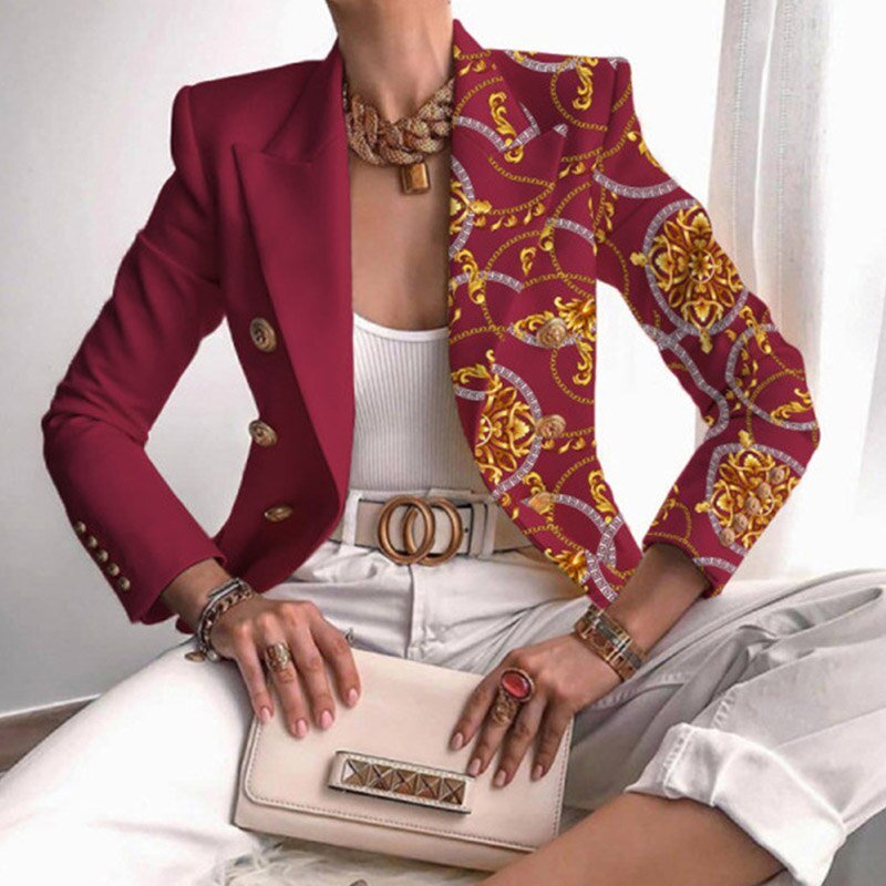 Frau in rotem Blazer mit Muster, weißem Top, weißer Hose, hält cremefarbene Clutch.