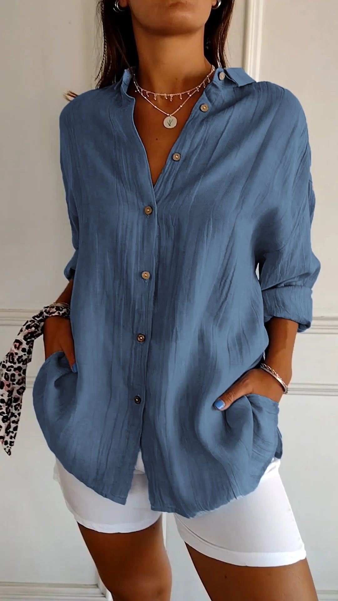 Frau in blauer Leinenbluse mit Knöpfen, weiße Hose, modisches Outfit, Freizeitkleidung.