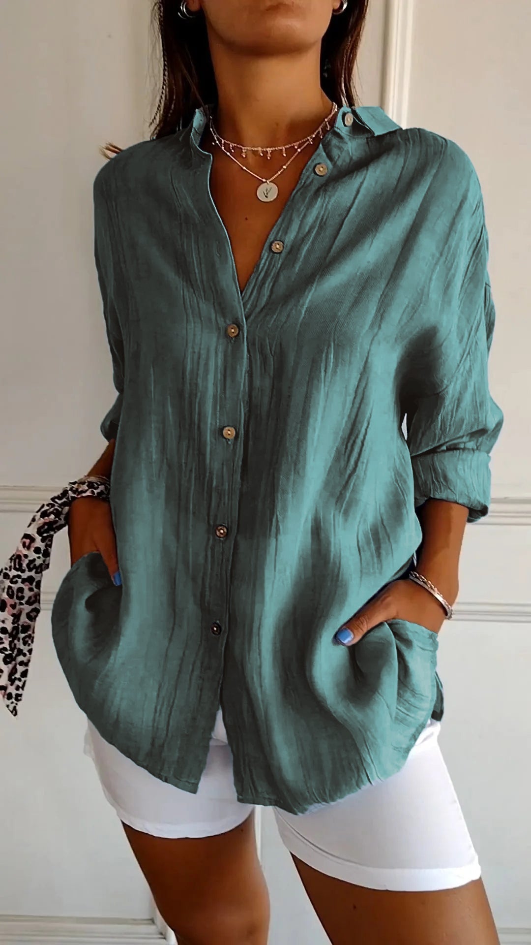 Frau in türkisfarbener Leinenbluse, lässig, modisch, Sommermode, weiße Hose.