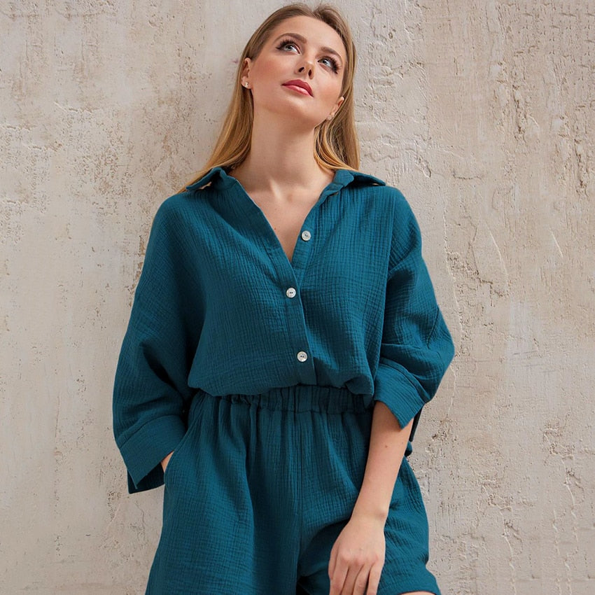 Frau in blauem Leinen-Overall vor beiger Wand, modisch, lässig, Sommerkleidung.